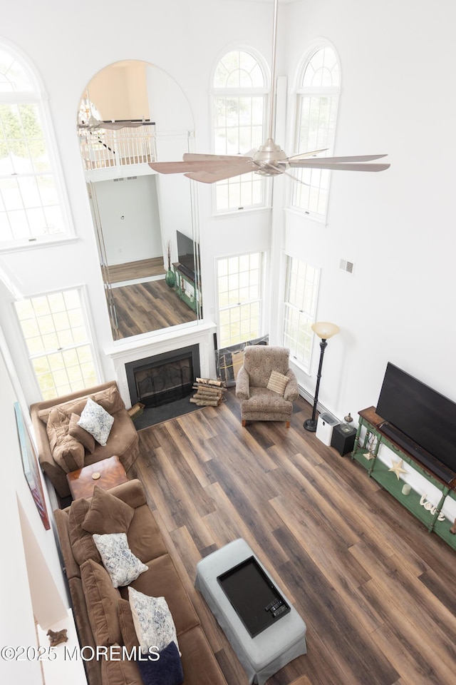 10 English Path, Freehold, NJ 07728 - living area featuring a towering ceiling, a glass covered fireplace, wood finished floors, and healthy amount of natural light