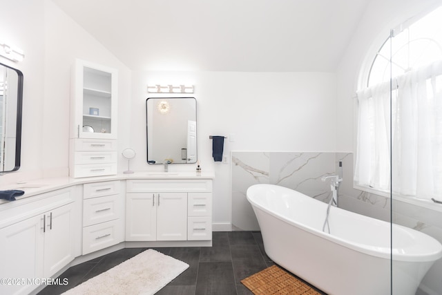 10 English Path, Freehold, NJ 07728 - bathroom featuring double vanity, tile walls, a freestanding tub, vaulted ceiling, and wainscoting