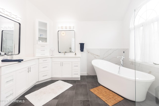 10 English Path, Freehold, NJ 07728 - bathroom featuring tile walls, a soaking tub, double vanity, and a wainscoted wall