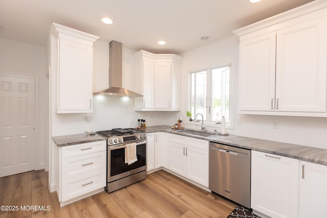 10 English Path, Freehold, NJ 07728 - kitchen featuring appliances with stainless steel finishes, wall chimney range hood, white cabinetry, light wood-style floors, and dark stone countertops