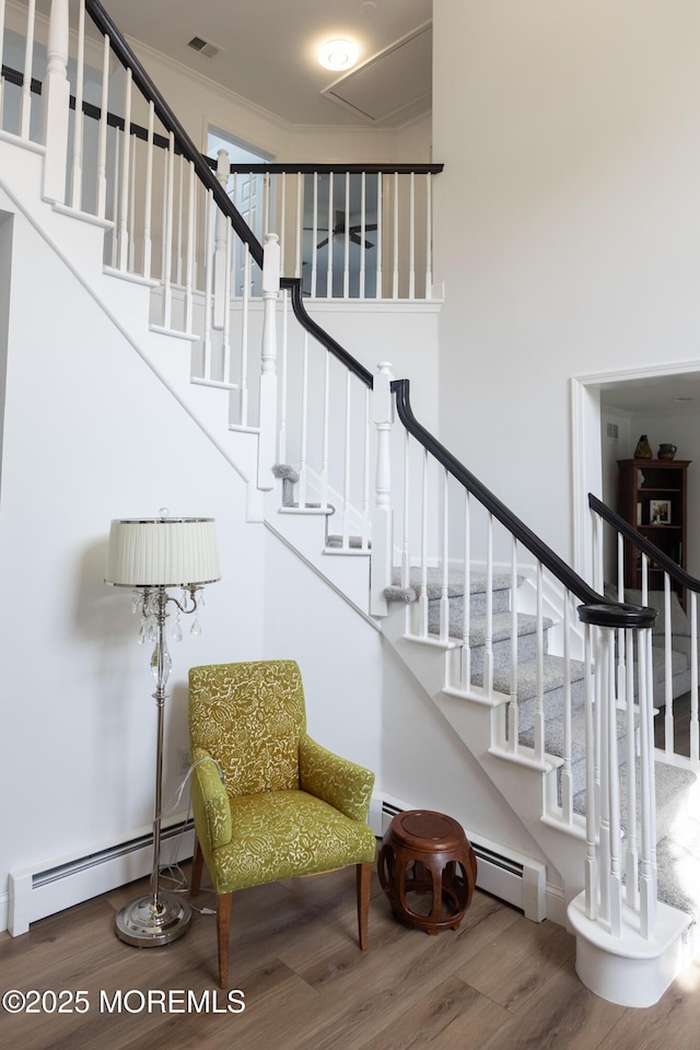 10 English Path, Freehold, NJ 07728 - stairs with a baseboard heating unit, wood finished floors, crown molding, and a towering ceiling