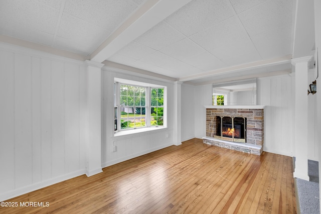 105 Cedar Grove Rd, Toms River, NJ 08753 - unfurnished living room with wood-type flooring, plenty of natural light, a stone fireplace, and a decorative wall