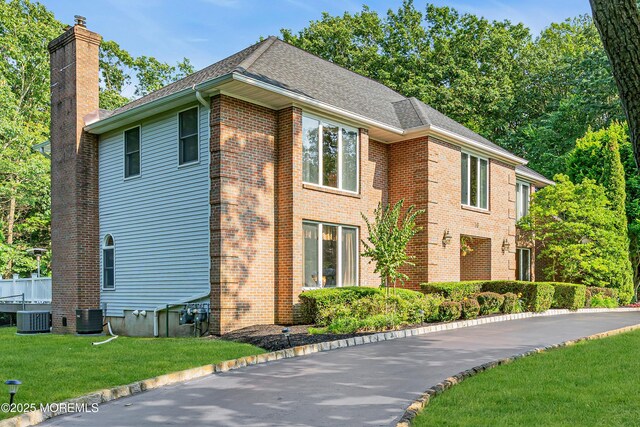 10 Cheryl Ln, Millstone, NJ 08510 - view of front of home featuring a front yard, brick siding, a chimney, and roof with shingles