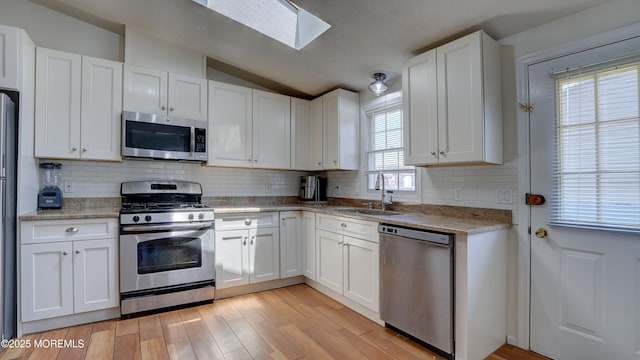 21 Parkview Way, Manalapan, NJ 07726 - kitchen featuring stainless steel appliances, a skylight, white cabinets, vaulted ceiling, and tasteful backsplash