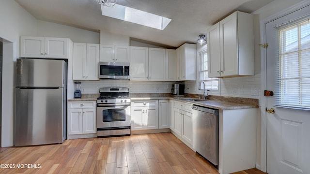 21 Parkview Way, Manalapan, NJ 07726 - kitchen with appliances with stainless steel finishes, vaulted ceiling, a skylight, white cabinets, and backsplash