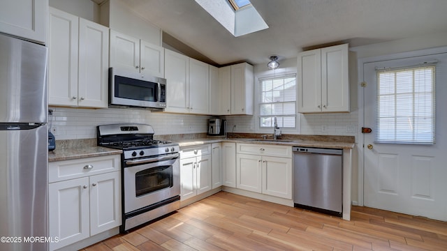 21 Parkview Way, Manalapan, NJ 07726 - kitchen featuring stainless steel appliances, a skylight, white cabinets, lofted ceiling, and backsplash