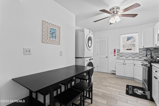 20 Highland Ave, Keansburg, NJ 07734 - kitchen featuring stacked washing machine and dryer, stainless steel gas range, ceiling fan, backsplash, and white cabinetry