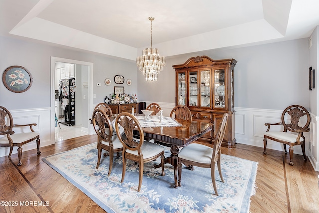 14 Tuscan Dr, Freehold, NJ 07728 - dining space with a chandelier, a wainscoted wall, a raised ceiling, light wood-style floors, and a decorative wall