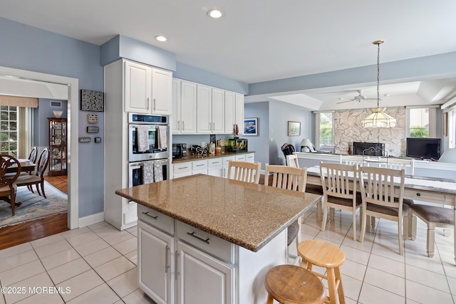 14 Tuscan Dr, Freehold, NJ 07728 - kitchen with light tile patterned floors, a kitchen bar, open floor plan, stainless steel double oven, and a kitchen island