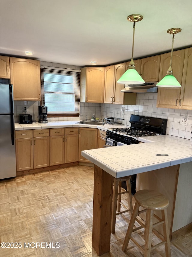 1801 Serpentine Dr, Forked River, NJ 08731 - kitchen with freestanding refrigerator, gas stove, wall chimney range hood, backsplash, and light brown cabinetry