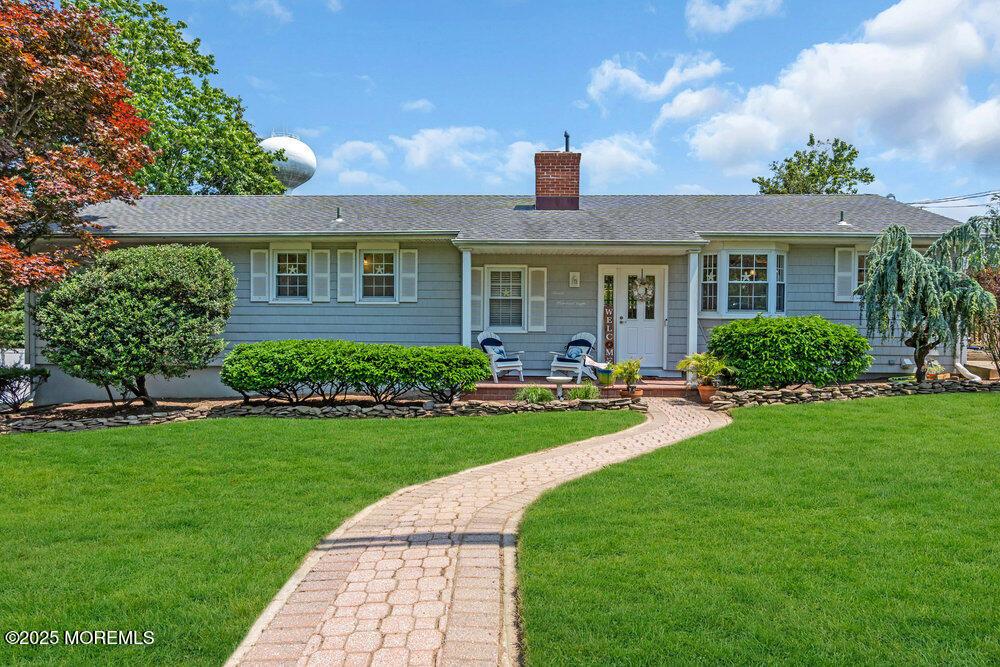 708 Schoolhouse Rd, Brielle, NJ 08730 - ranch-style home featuring a chimney, a front yard, a shingled roof, and a porch
