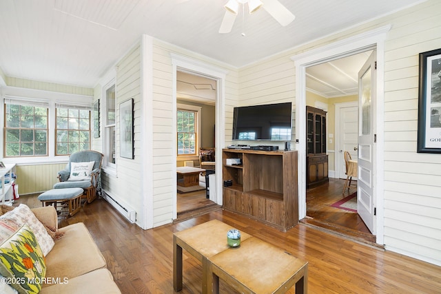 699 River Rd, Fair Haven, NJ 07704 - living area featuring baseboard heating, wooden walls, wood finished floors, plenty of natural light, and ornamental molding