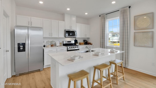 17 Chapman Ave, Neptune Township, NJ 07753 - kitchen with appliances with stainless steel finishes, a sink, light wood-type flooring, white cabinets, and a kitchen bar