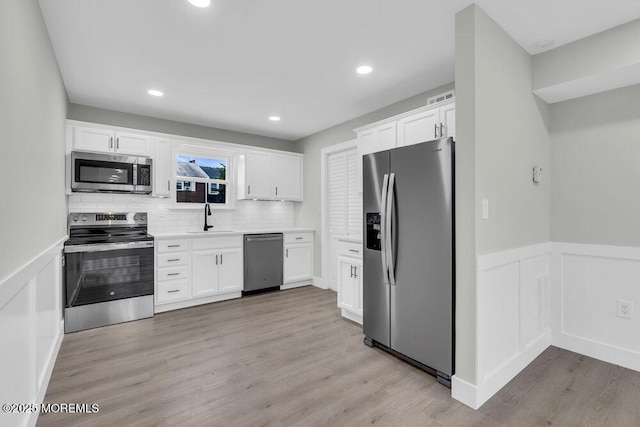 84 Briar Mills Dr, Brick, NJ 08724 - kitchen featuring appliances with stainless steel finishes, a sink, white cabinets, a wainscoted wall, and light countertops