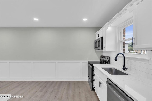 84 Briar Mills Dr, Brick, NJ 08724 - kitchen featuring appliances with stainless steel finishes, a sink, white cabinetry, light stone counters, and wainscoting