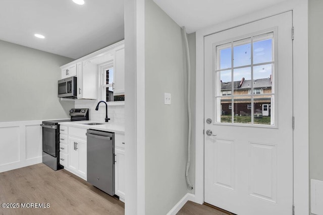 84 Briar Mills Dr, Brick, NJ 08724 - kitchen featuring stainless steel appliances, a sink, light wood finished floors, white cabinetry, and wainscoting