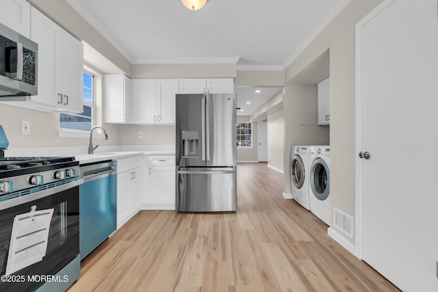 34-1 Green Grove Ave, Keyport, NJ 07735 - kitchen with stainless steel appliances, washing machine and clothes dryer, crown molding, light wood-style floors, and white cabinetry