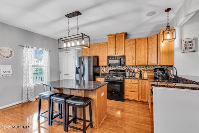 9 Olivia Dr, Tinton Falls, NJ 07712 - kitchen featuring black appliances, decorative backsplash, light wood finished floors, a center island, and a kitchen breakfast bar