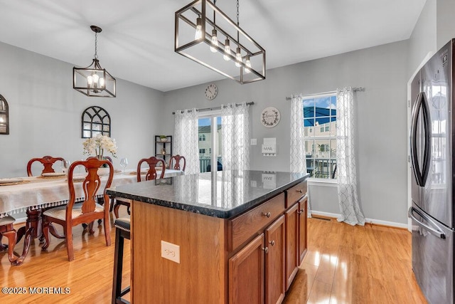 9 Olivia Dr, Tinton Falls, NJ 07712 - kitchen with freestanding refrigerator, light wood-style floors, brown cabinets, a breakfast bar, and a chandelier