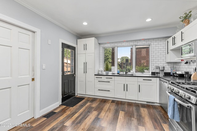51 Oakland St, Red Bank, NJ 07701 - kitchen featuring stainless steel appliances, dark countertops, a sink, decorative backsplash, and crown molding