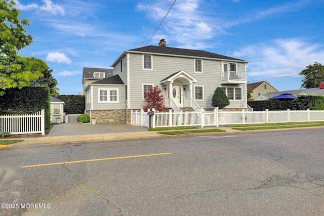 206 Chicago Ave, Point Pleasant Beach, NJ 08742 - colonial inspired home with stone siding, a chimney, a fenced front yard, and a balcony