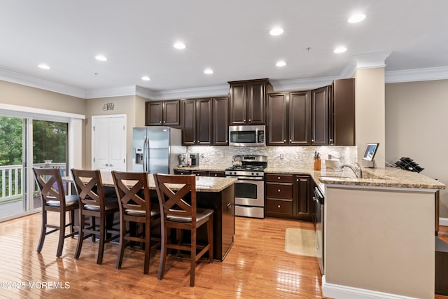 38 Phillip E Frank Way Unit 38, Cliffwood, NJ 07721 - kitchen with stainless steel appliances, a kitchen island, a breakfast bar area, dark brown cabinets, and crown molding