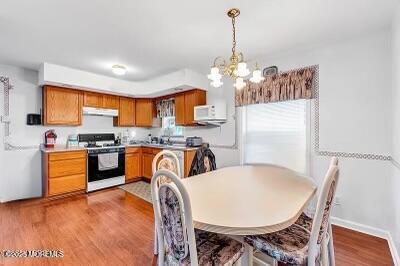 532 Georgia Tavern Rd, Howell, NJ 07731 - kitchen featuring gas range, exhaust hood, a chandelier, wood finished floors, and pendant lighting