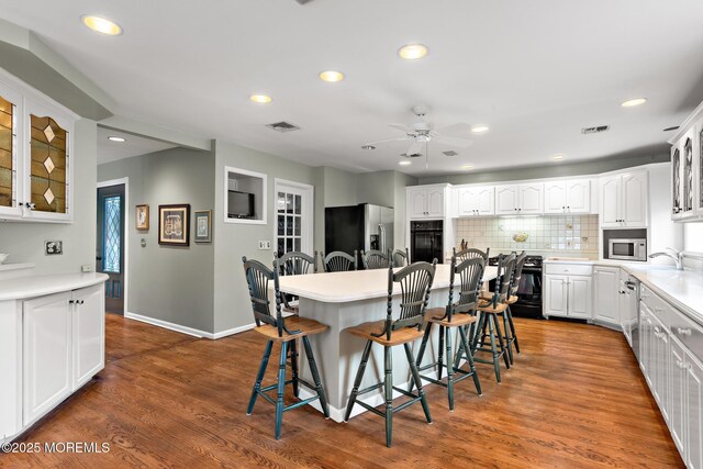 14 W St, Monmouth Beach, NJ 07750 - kitchen featuring black appliances, a kitchen breakfast bar, ceiling fan, glass insert cabinets, and white cabinetry