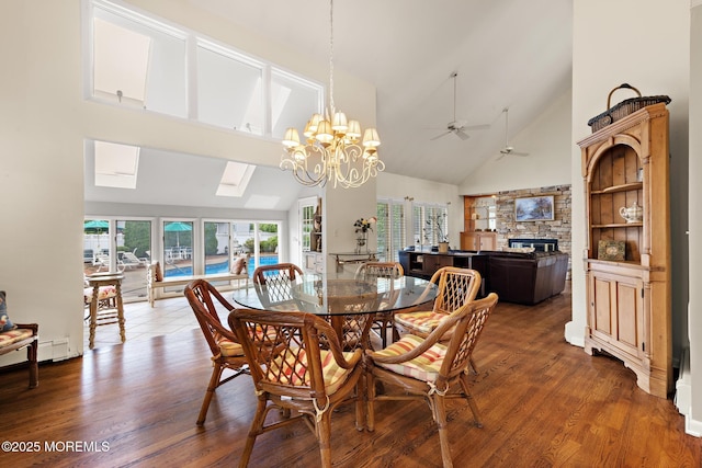 14 W St, Monmouth Beach, NJ 07750 - dining room with high vaulted ceiling, a ceiling fan, a stone fireplace, wood finished floors, and a chandelier