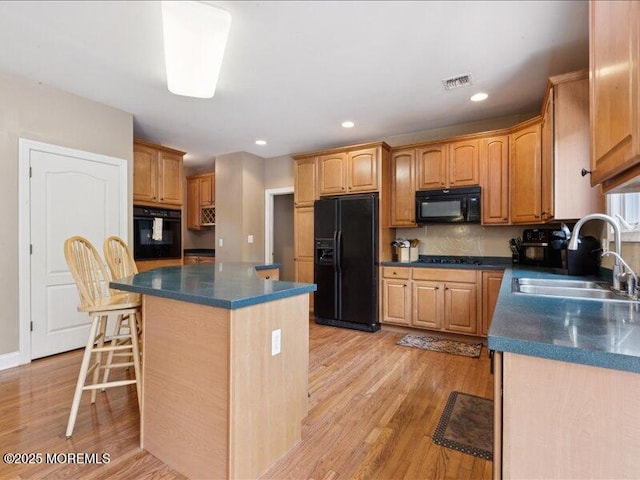 1 Turtle Clan Ct, Clarksburg, NJ 08510 - kitchen with black appliances, dark countertops, a center island, light wood-style flooring, and a kitchen breakfast bar