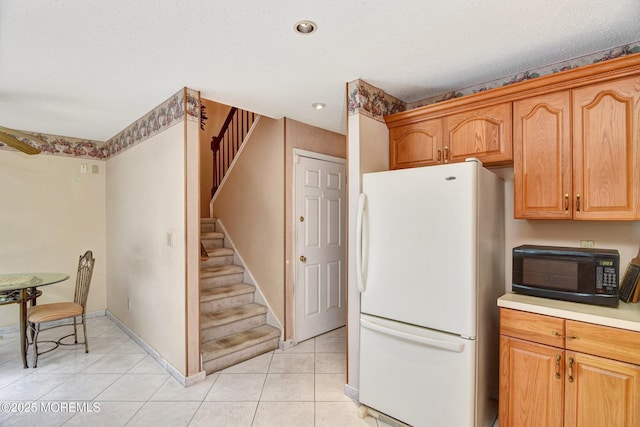 28 Tulip Ct, Howell, NJ 07731 - kitchen with freestanding refrigerator, black microwave, light tile patterned flooring, light countertops, and baseboards