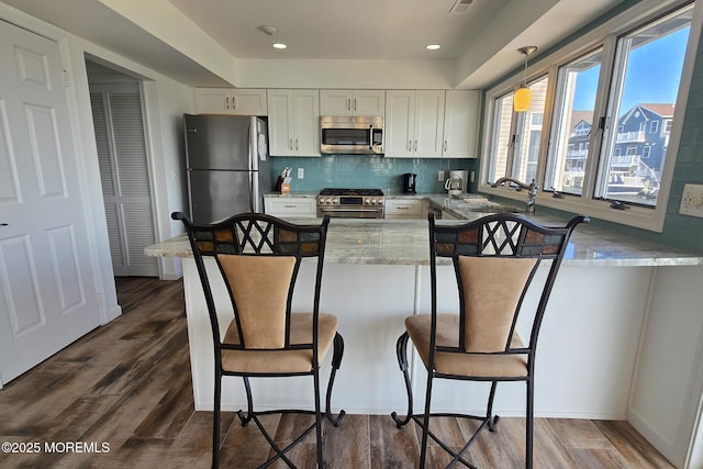 443 Harding Ave, Ortley Beach, NJ 08751 - kitchen featuring appliances with stainless steel finishes, a kitchen breakfast bar, light stone counters, white cabinetry, and recessed lighting