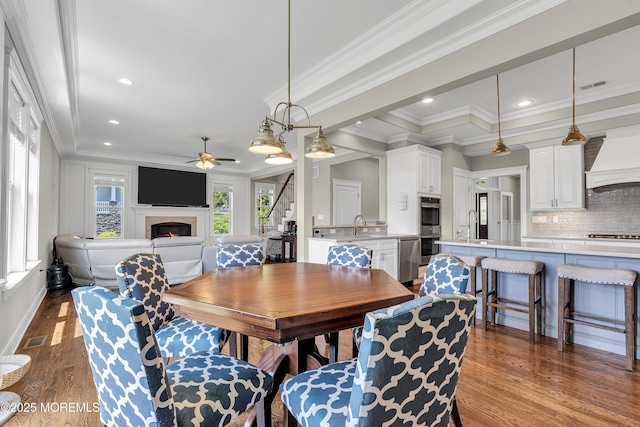 1605 Lakewood Rd, Manasquan, NJ 08736 - dining area featuring a ceiling fan, a lit fireplace, dark wood-type flooring, crown molding, and stairs