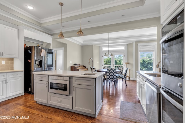 1605 Lakewood Rd, Manasquan, NJ 08736 - kitchen featuring appliances with stainless steel finishes, dark wood-style floors, light countertops, hanging light fixtures, and ornamental molding