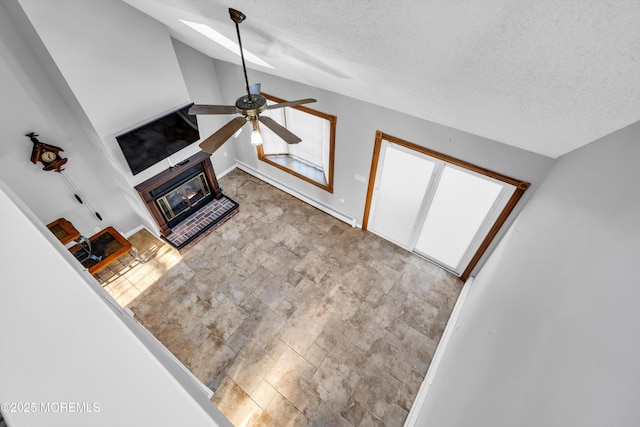 91 Wind Jammer Ct, Bayville, NJ 08721 - unfurnished living room with ceiling fan, a textured ceiling, a glass covered fireplace, stone finish flooring, and lofted ceiling