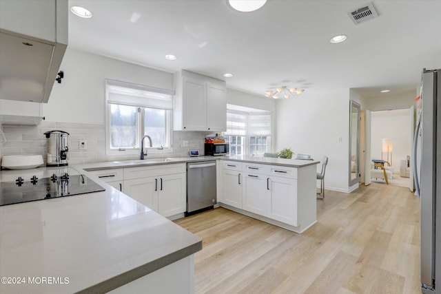 12 Harbor Ct, West Long Branch, NJ 07764 - kitchen with black appliances, decorative backsplash, a peninsula, white cabinets, and recessed lighting