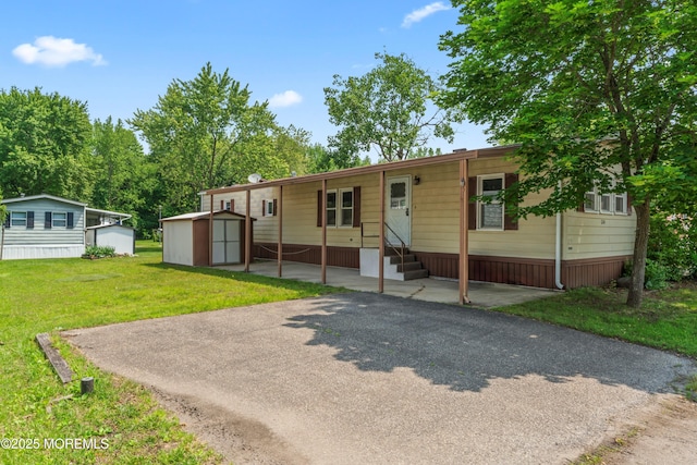 124 Village Rd, Morganville, NJ 07751 - manufactured / mobile home featuring entry steps, a storage shed, and a front lawn