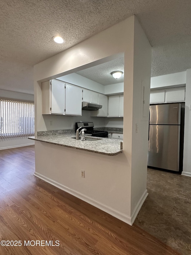 115 Brandywine Ct Unit 115, Brick, NJ 08724 - kitchen with appliances with stainless steel finishes, a textured ceiling, under cabinet range hood, white cabinetry, and dark wood finished floors