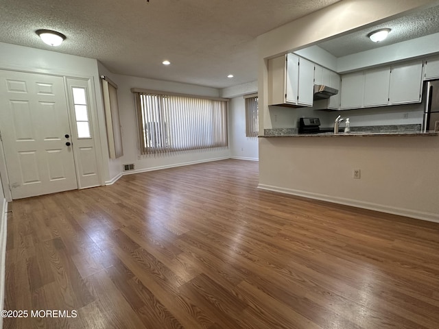 115 Brandywine Ct Unit 115, Brick, NJ 08724 - kitchen featuring under cabinet range hood, dark wood-style flooring, a textured ceiling, freestanding refrigerator, and white cabinets