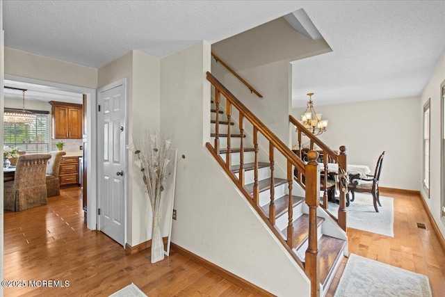 519 Gilford Ave, Toms River, NJ 08753 - stairway featuring a chandelier, wood finished floors, and a textured ceiling