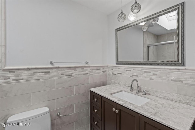 519 Gilford Ave, Toms River, NJ 08753 - bathroom featuring vanity, tile walls, tiled shower, a skylight, and a wainscoted wall
