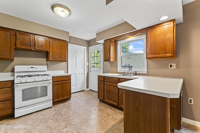 76 9th St, Belford, NJ 07718 - kitchen featuring white gas range oven, light countertops, a peninsula, and brown cabinetry