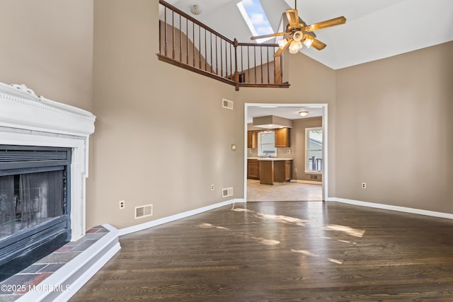 76 9th St, Belford, NJ 07718 - unfurnished living room with ceiling fan, wood finished floors, a skylight, a tiled fireplace, and high vaulted ceiling