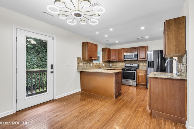 1217 Madison Ave, Toms River, NJ 08757 - kitchen with appliances with stainless steel finishes, light wood-type flooring, backsplash, a peninsula, and a chandelier