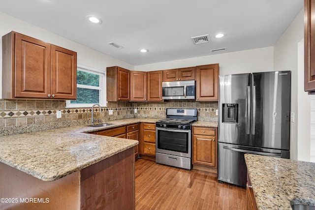 1217 Madison Ave, Toms River, NJ 08757 - kitchen with stainless steel appliances, light wood-style floors, a peninsula, light stone counters, and backsplash