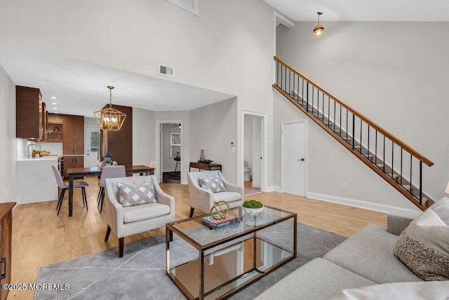 8 Eunice Ter, West Long Branch, NJ 07764 - living room featuring a chandelier, light wood finished floors, high vaulted ceiling, and stairs