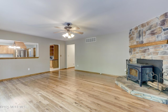 143 Siloam Rd, Freehold, NJ 07728 - unfurnished living room featuring a wood stove, light wood-type flooring, ceiling fan, and a chandelier