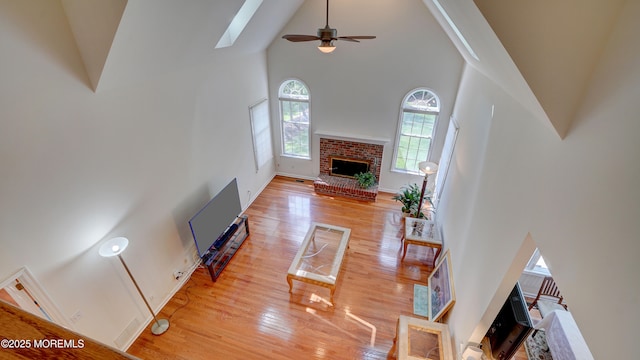 88 Vanderveer Dr, Basking Ridge, NJ 07920 - living area with high vaulted ceiling, a brick fireplace, light wood finished floors, ceiling fan, and a skylight