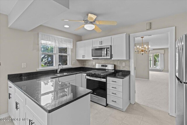 50 Normanton Ave, Manchester, NJ 08759 - kitchen with stainless steel appliances, white cabinets, a peninsula, a chandelier, and dark stone counters