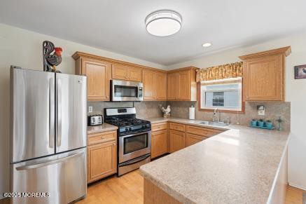 169 Pulaski Blvd, Toms River, NJ 08757 - kitchen featuring stainless steel appliances, a peninsula, light countertops, tasteful backsplash, and light wood finished floors